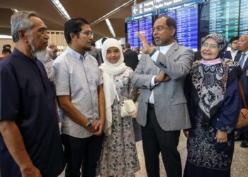 ZAMBRY Abd. Kadir beramah mesra dengan rakyat Malaysia, Mohamad Azim Rosli (dua kiri) bersama ahli keluarga yang menyambut ketibaan rakyat Malaysia dari Sudan di KLIA, Sepang. - UTUSAN/FAISOL MUSTAFA