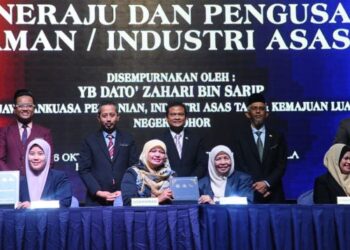 ZAHARI Sarip (berdiri, tengah) menyaksikan pertukaran dokumen pada Program Kolaborasi Di Antara Syarikat Peneraju dan Pengusaha Tanaman dan Industri Asas Tani yang diadakan di Hotel Holiday Villa, Johor Bahru. - FOTO/RAJA JAAFAR ALI