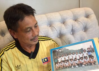 ZULKIFLI Hamzah menunjukkan gambar kenangan bersama pasukan Terengganu pada tahun 1982 di rumahnya di Kuala Ibai, Kuala Terengganu, baru-baru ini. - UTUSAN/TENGKU DANISH BAHRI TENGKU YUSOFF
