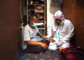 PETUGAS perubatan memeriksa pesakit Covid-19 yang menjalani kuarantin kendiri di rumah di Bandung, Indonesia. - AFP