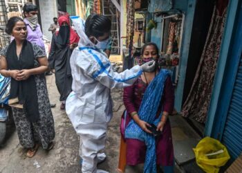 PETUGAS perubatan melakukan ujian saringan Covid-19 terhadap seorang wanita di Mumbai, India. - AFP