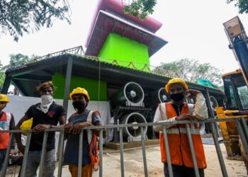 PEKERJA berdiri di depan menara jerebu setinggi 25 meter di New Delhi. - AFP