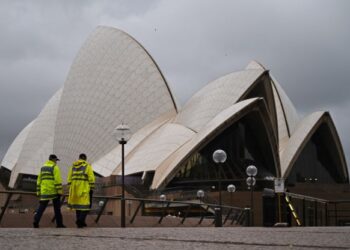 ANGGOTA polis berjalan melepasi Sydney Opera House di Sydney. - AFP