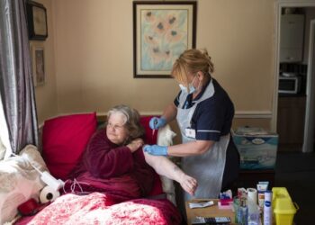 PETUGAS perubatan menyuntik vaksin AstraZeneca kepada seorang wanita ketika melakukan program vaksinasi dari rumah ke rumah di Chesterfield, England. - AFP