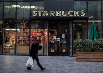 SEORANG penduduk berjalan di depan kedai kopi Starbucks di Beijing. - AFP