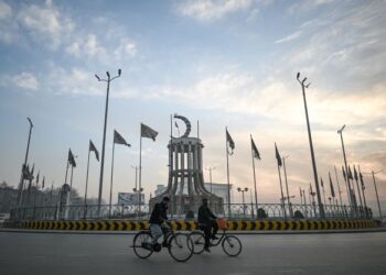DUA penduduk mengayuh basikal di depan Dataran Abdul Haq yang dihiasi dengan bendera Taliban di Kabul, Afghanistan. - AFP
