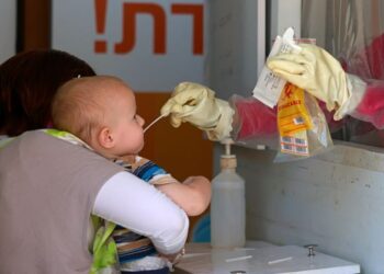 PETUGAS kesihatan melakukan ujian Covid-19 terhadap seorang bayi di Baitulmuqaddis, Palestin. - AFP