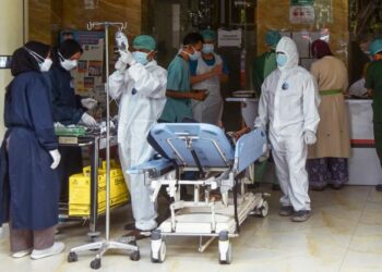 PETUGAS kesihatan memeriksa keadaan pesakit yang dijangkiti Covid-19 di hospital di Bekasi, Jakarta Timur. - AFP
