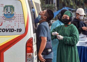 PETUGAS kesihatan melakukan ujian Covid-19 terhadap seorang lelaki secara mobil di stesen kereta api di Bekasi, Jakarta Timur. - AFP