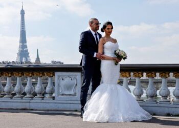 PASANGAN pengantin bergambar di jambatan Alexandre III dengan berlatar belakang Menara Eiffel di Paris, Perancis pada Mac 2021.  Kajian di Britain mendapati pasangan yang mengadakan majlisd kahwin besar-besaran akan lebih cepat bercerai. - AFP