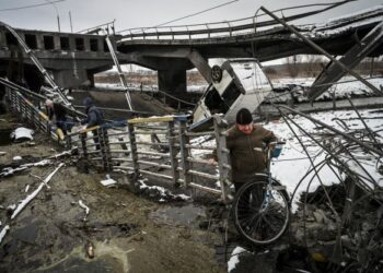 PENDUDUK awam berjalan di tepi sungai yang menyaksikan struktur jambatan musnah akibat pertempuran di utara Kyiv, Ukraine. - AFP