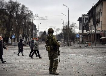PENDUDUK Ukraine berjalan melintasi anggota tentera Rusia di bandar Mariupol. - AFP