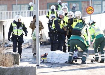 POLIS dan petugas kesihatan mengangkat seorang lelaki yang cedera akibat terkena tembakan di kaki ketika rusuhan di bandar Norrkoping, Sweden. - AFP