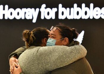 SEORANG wanita memeluk ahli keluarganya sebelum berlepas ke New Zealand di Lapangan Terbang Antarabangsa Sydney, Australia. - AFP