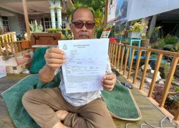MD. DERIS Salleh menunjukkan laporan polis yang dibuatnya di Balai Polis Tanjung Kling, Melaka. - UTUSAN/AMRAN MULUP