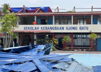 ANGGOTA Angkatan Pertahanan Awam Malaysia (APM) negeri membantu memasang kanvas pada bahagian bumbung blok yang terjejas akibat ribut di Sekolah Kebangsaan Ujong Batu, Kangar, Perlis. -UTUSAN/ASYRAF MUHAMMAD