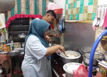 SITI Nur Atiqah Othman dibantu adiknya, Muhammad Aiman memasak pulut untuk dibuat ketupat sebagai juadah hari raya di Taman Ria Jaya, Sungai Petani, malam tadi. - UTUSAN/OTHMAN YAHAYA