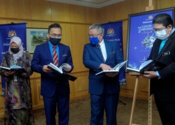 ADHAM Baba (dua dari kanan) melihat buku 'The Covid-19 Chronicles Of Malaysia-Navigating The Storm' di Kementerian Kesihatan Malaysia di Putrajaya, hari ini. - UTUSAN/FAISOL MUSTAFA