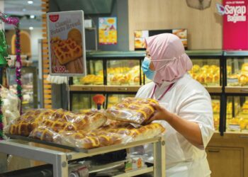 SEORANG kakitangan AEON menyusun roti yang dijual di pasar raya berkenaan. – GAMBAR HIASAN