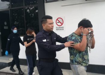 YAW CHERN FONG (depan) dan isterinya, Phang Siew Wei diiringi polis ketika didakwa di Mahkamah Majistret Kulai hari ini..