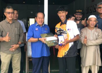 AHMAD Maslan (dua kiri) menyampaikan sumbangan kepada pemenang pingat gangsa Sukan SEA acara Petanque, Muhammad Arif Kana di Benut, Pontian, semalam.