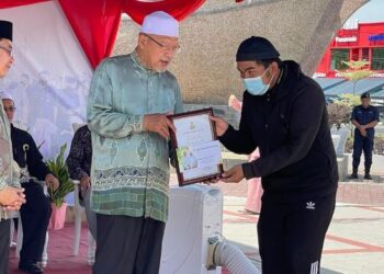 AHMAD Yakub (tengah) menyampaikan sumbangan insentif kepada pelajar cemerlang di majlis perasmian Dataran Tok Bali di Pasir Puteh, Kelantan, hari ini. - FOTO/TOREK SULONG