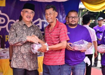 MOHD. Ali Mohd. Rustam (kiri) menyampaikan agihan daging korban kepada salah seorang asnaf sambil diiringi Mohd. Najib Mohd. Noor.