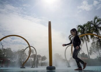 KUALA LUMPUR, 20 JULAI 2022: Seorang kanak-kanak melewati pancuran air di taman air ketika cuaca panas yang melanda sejak beberapa hari lalu dalam tinjauan di Taman Tasik Titiwangsa di sini, hari ini. - UTUSAN/MUHAMAD IQBAL ROSLI