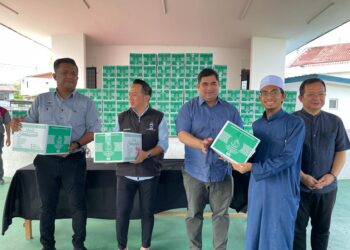 SHAHELMEY Yahya (tengah) menyampaikan set kelengkapan pengurusan jenazah kepada salah seorang penerima di Balai Terbuka Kampung Tanjung Aru, hari ini.