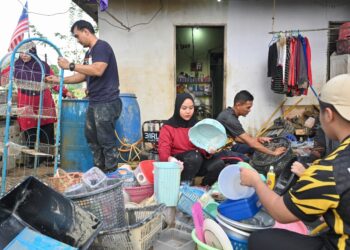 PENDUDUK membersihkan barangan yang ditenggelami air di Kampung Durian Mentangau, Paka, Dungun, Terengganu, hari ini. - UTUSAN/PUQTRA HAIRRY ROSLI