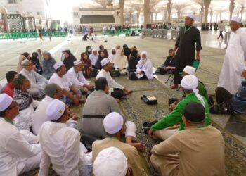 IZUDIN Muhamad Amin (berdiri, kiri) memberi penerangan kepada jemaah Malaysia di pekarangan Masjid Nabawi, Madinah.