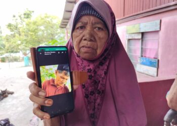 KHATIJAH @ Mariam Yahaya menunjukkan gambar Abdul Razak Kamarudin yang hilang sejak 27 Jun lalu ketika ditemui pemberita di rumahnya di Felda Pasir Besar, Tampin, Negeri Sembilan. - UTUSAN/NOR AINNA HAMZAH