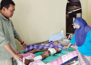 KAMARUDDIN Kassim (kiri) dan Zuraidah Ariffin bersama Mohd. Faizal yang terlantar akibat kemalangan lebih lima bulan lalu ketika ditemui di Kampung Padang Lebar, Sungai Layang, Rembau, Negeri Sembilan, baru-baru ini. - UTUSAN/NOR AINNA HAMZAH
