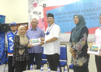 ANNUAR Musa (tengah) menyerahkan peranti kepada seorang penerima di PEDi Felda Bukit Cherakah, Kuala Selangor, Selangor. -UTUSAN/ ISKANDAR SHAH MOHAMED