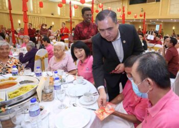 Anthony Loke menyerahkan angpau kepada warga emas dari Charis Old Folks Home pada Majlis Tautan Mesra dan Perpaduan Kementerian Pengangkutan di Putrajaya  hari ini. - UTUSAN/FAISOL MUSTAFA