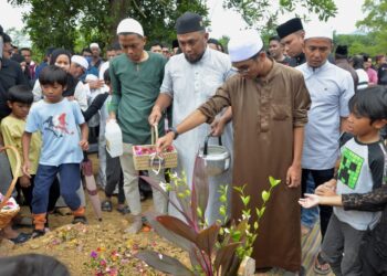 AHLI keluarga menyiram air di kubur Allahyarham Muhamad Hafez Jamal Jamaludin semasa pengkebumian di Tanah Perkuburan Islam Meru Raya di  Ipoh, Perak,  hari ini. - UTUSAN/ZULFACHRI ZULKIFLI