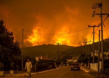 PENDUDUK tempatan berjalan di kampung Gouves, Pulau Euboea, Greece yang dilatari kebakaran hutan. -AFP