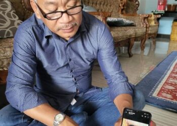AWANG Asim Ampuan Yaacub menunjukkan gambar arwah Awang Askandar Ampuan Yaacub semasa 
ditemui di Kampung Benoni, Papar semalam.