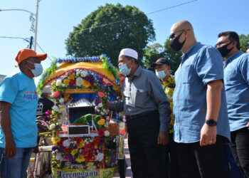 ARIFFIN Deraman (berkopiah) mendengar keluhan pengayuh beca, Abdullah Mohammad, 64, pada majlis penyerahan pakaian kepada pengayuh beca di Pasar Besar Kedai Payang, Kuala Terengganu, hari ini. FOTO: PUQTRA HAIRRY.