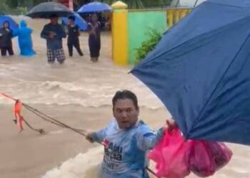 MOHD. Salleh Ishak mengharung arus deras membawa makanan bagi penghuni PPS SK Seri Bali di Chaah, Segamat.