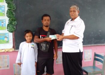 JUSRI Wan (tengah) bersama anaknya, Zurina (kiri) menerima bantuan awal persekolahan daripada Abd. Manaf Mat (kanan) di Sekolah Kebangsaan (SK) Sungai Kiol di Jerantut, Pahang.  - UTUSAN/HARIS FADILAH AHMAD