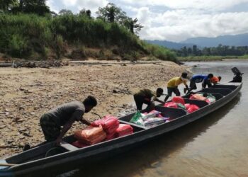 PENDUDUK Orang Asli etnik Bateq sedang menurunkan barang keperluan dapur daripada bot sumbangan pertubuhan bukan kerajaan (NGO) di Kampung Yong, Kuala Tahan di Jerantut, Pahang. - FOTO/HARIS FADILAH AHMAD