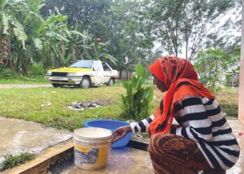 SEORANG penduduk Orang Asli, Maria Manggis menadah air hujan di hadapan rumahnya di Kampung Pasir Linggi, Pos Lebir, Gua Musang, Kelantan.-UTUSAN/ AIMUNI TUAN LAH