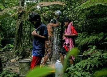 ORANG Asli suku Temuan, Roslan Mohamed, 59, bersama anak-anaknya mandi menggunakan air perigi yang turut digunakan untuk kegunaan harian penduduk Kampung Orang Asli Air Kuning, Bukit Bandaraya, Shah Alam, Selangor, semalam. – UTUSAN/ZULFADHLI ZAKI