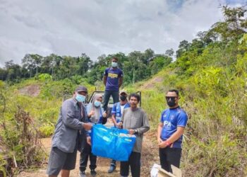 ROSLAN Abu Kassim (kiri) bersama sukarelawan Bird Group Taman Negara (BGTN) dan Angkatan Pertahanan Awam Malaysia (APM) menurunkan barang keperluan dapur untuk sumbangan kepada penduduk Orang Asli etnik Bateq di Kampung Dedari di Jerantut, Pahang. - UTUSAN/HARIS FADILAH AHMAD