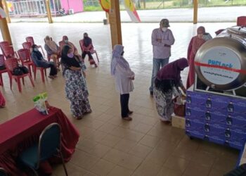 PENDUDUK berbaris untuk mengambil beras percuma daripada mesin ATM khas di YKK, Ketereh, Kota Bharu. - UTUSAN/ROHANA MOHD. NAWI