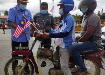 ABDUL Azeez Abdul Rahim (kiri) melekatkan Jalur Gemilang di motosikal pada Program Kempen Kibarkan Jalur Gemilang di Pekan Baling, Kedah, baru-baru ini.