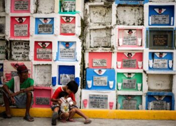 SEORANG kanak-kanak lelaki memberi minum kepada adiknya di depan kubur bertingkat di tanah perkuburan Kabihasnan, Manila.-AFP