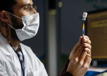 SEORANG petugas kesihatan Israel menyediakan dos vaksin Covid-19 untuk orang ramai yang beratur di sebuah klinik di Baitulmuqaddis. - AFP