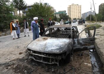 ANGGOTA Taliban memeriksa bangkai kereta yang musnah selepas beberapa serangan roket dilancarkan di Kabul, Afghanistan. - AFP